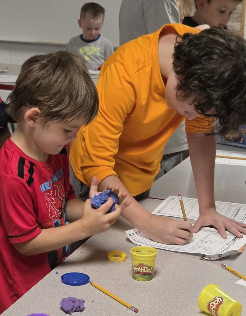Fifth-grade students help kindergarten students build their own brooms during a Halloween-themed STEM challenge after reading Room on the Broom.