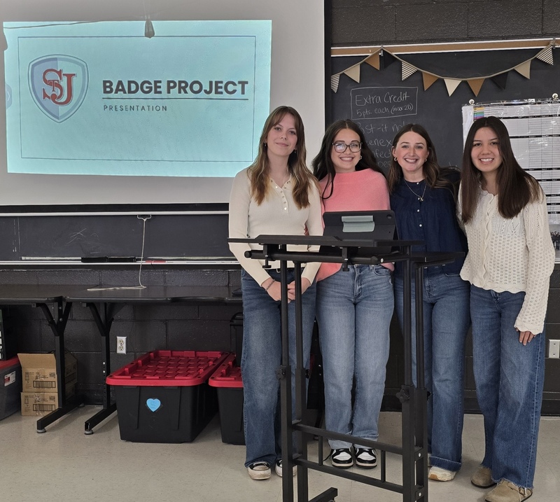 Four girls stand behind a podium. 