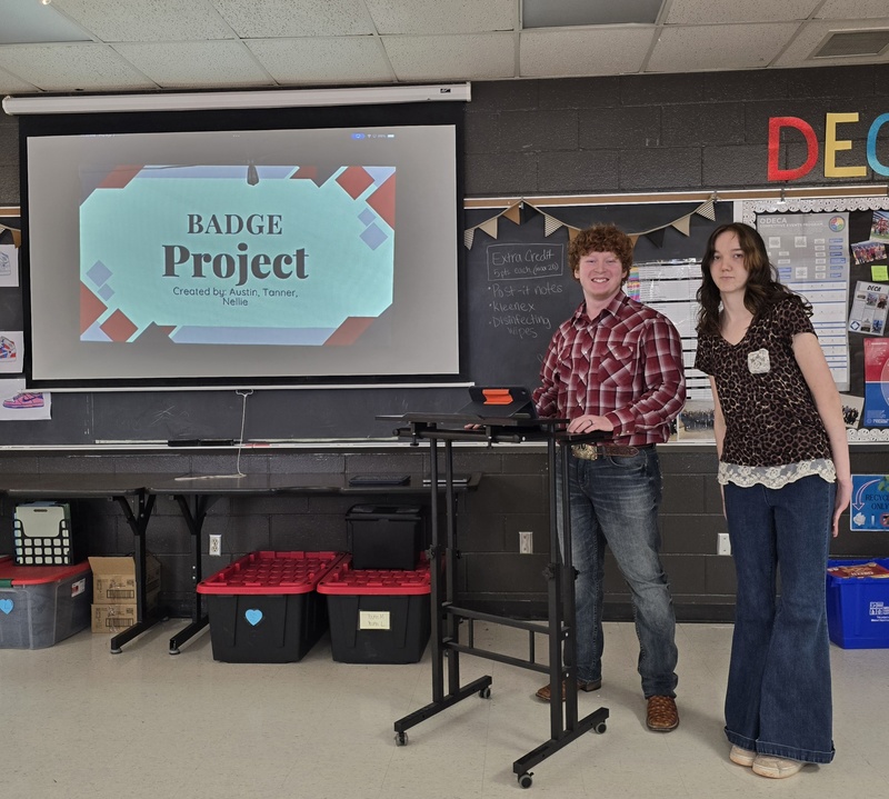 Students stand at front of classroom in front of board to give presentation! 