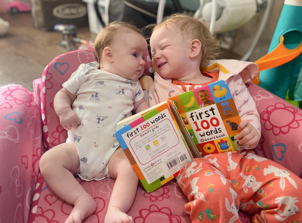 Two young children explore a board book together