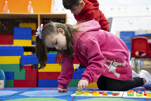 Preschooler sitting on floor working on a wood puzzle