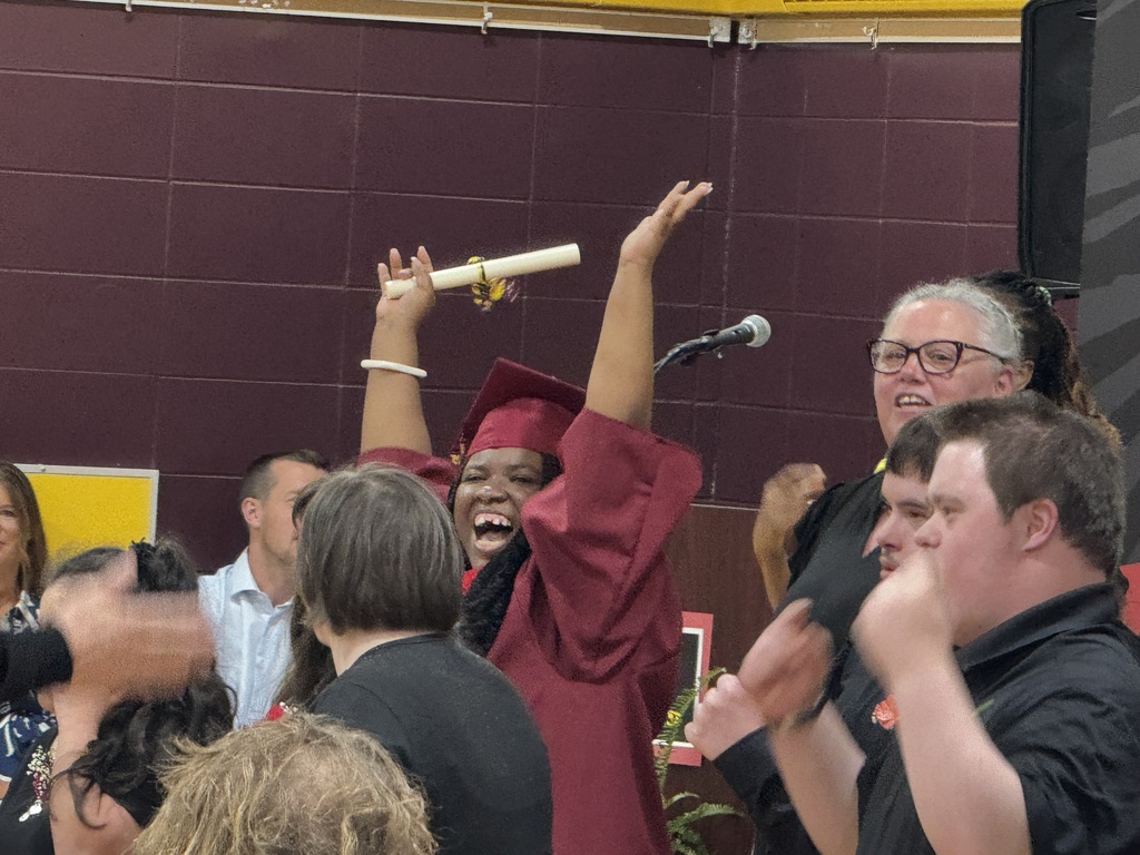 A Woodland student smiling with their hands raised in the air