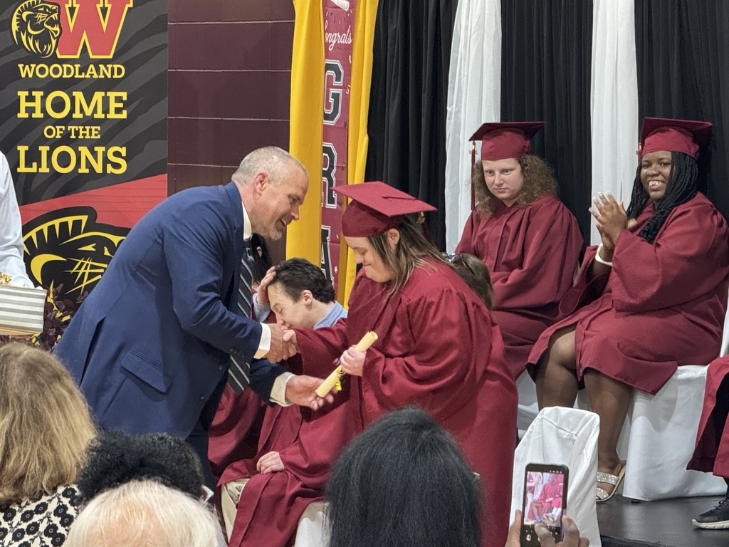 Assistant principal Ethan Barden hands a scroll to a Woodland student
