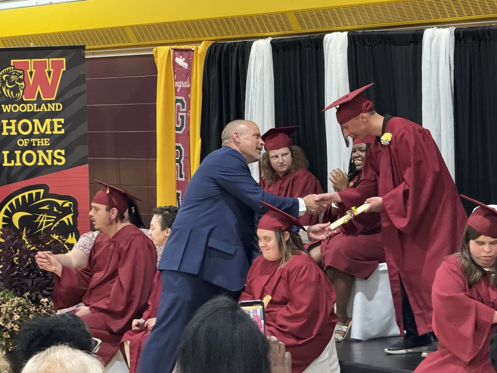 Assistant principal Ethan Barden hands a scroll to a Woodland student