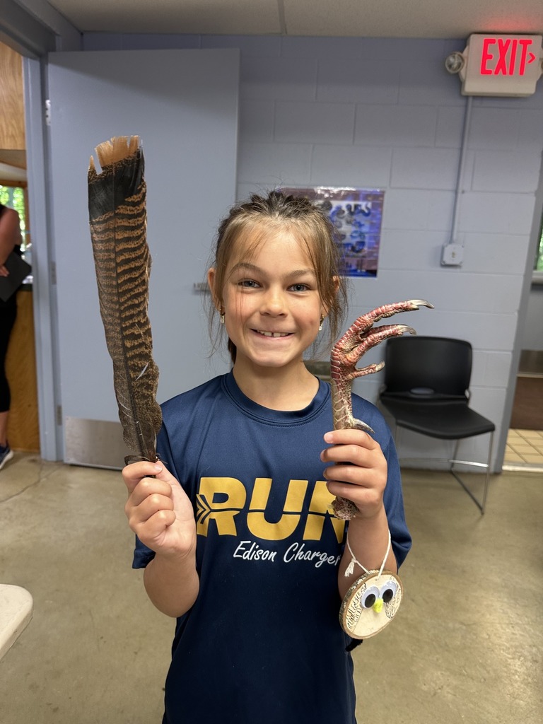 A students holds up a bird feather and talon