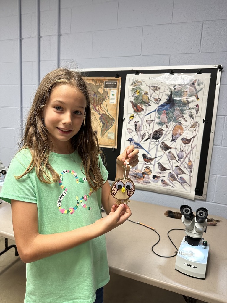 A student holds their owl craft
