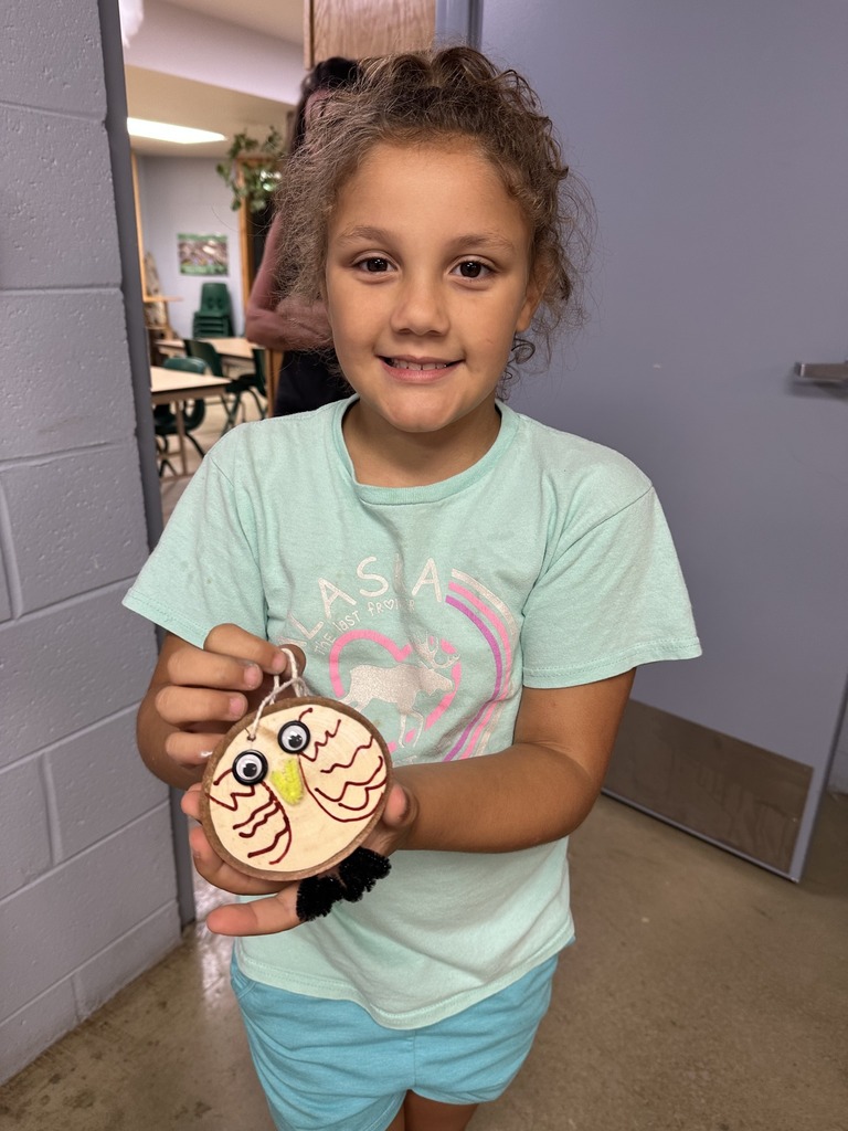 A student holds their owl craft