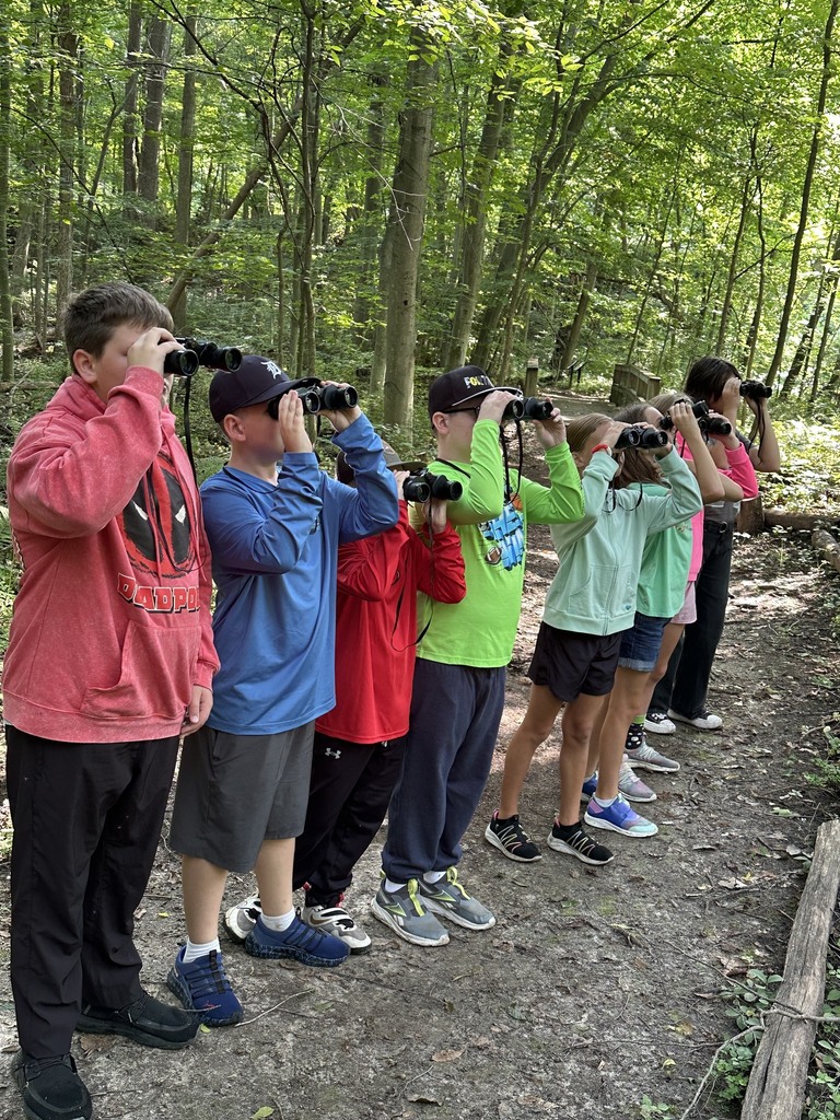 A row of students holding binoculars to their faces