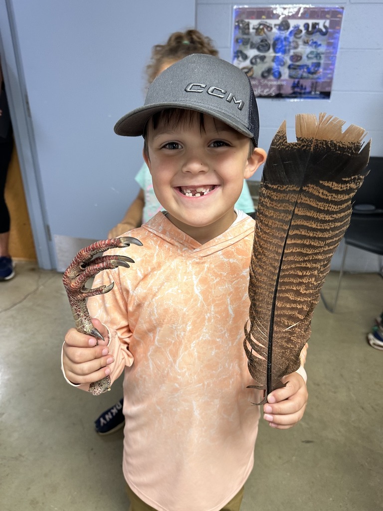 A students holds up a bird feather and talon