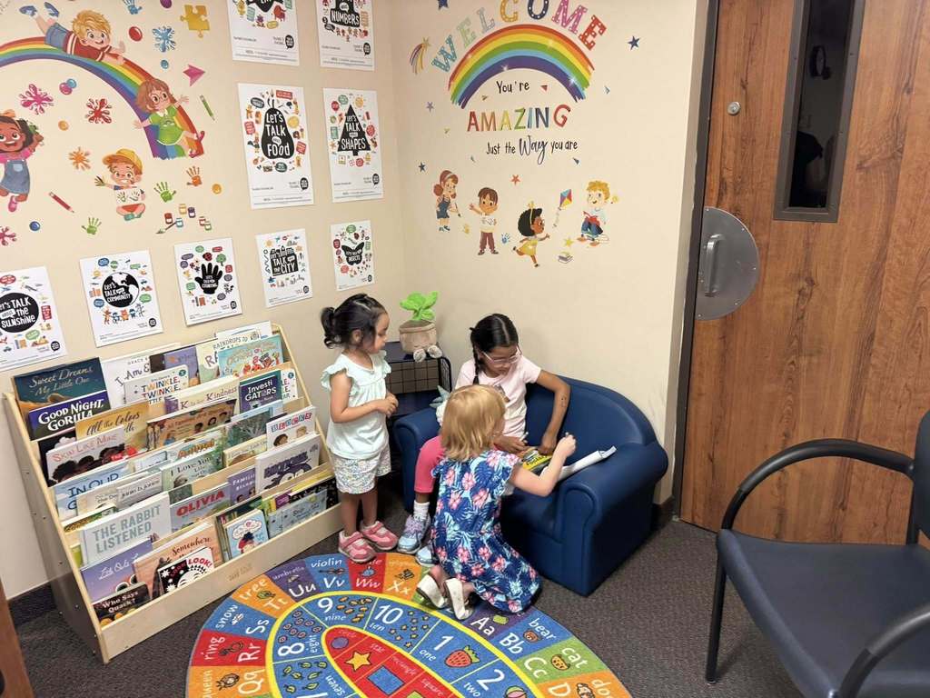 Three young children sit in the next Talking is Teaching space at the Early Childhood Court.