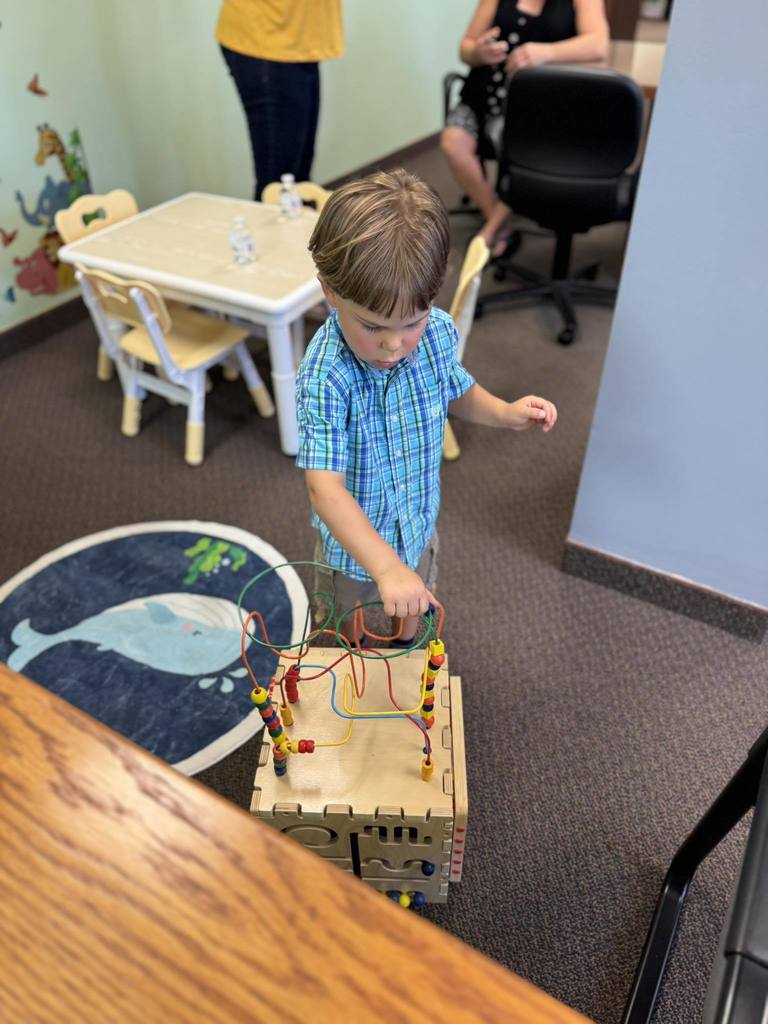 A young boy plays with a wood toy at the Talking is Teaching space at the Early Childhood Court waiting room.