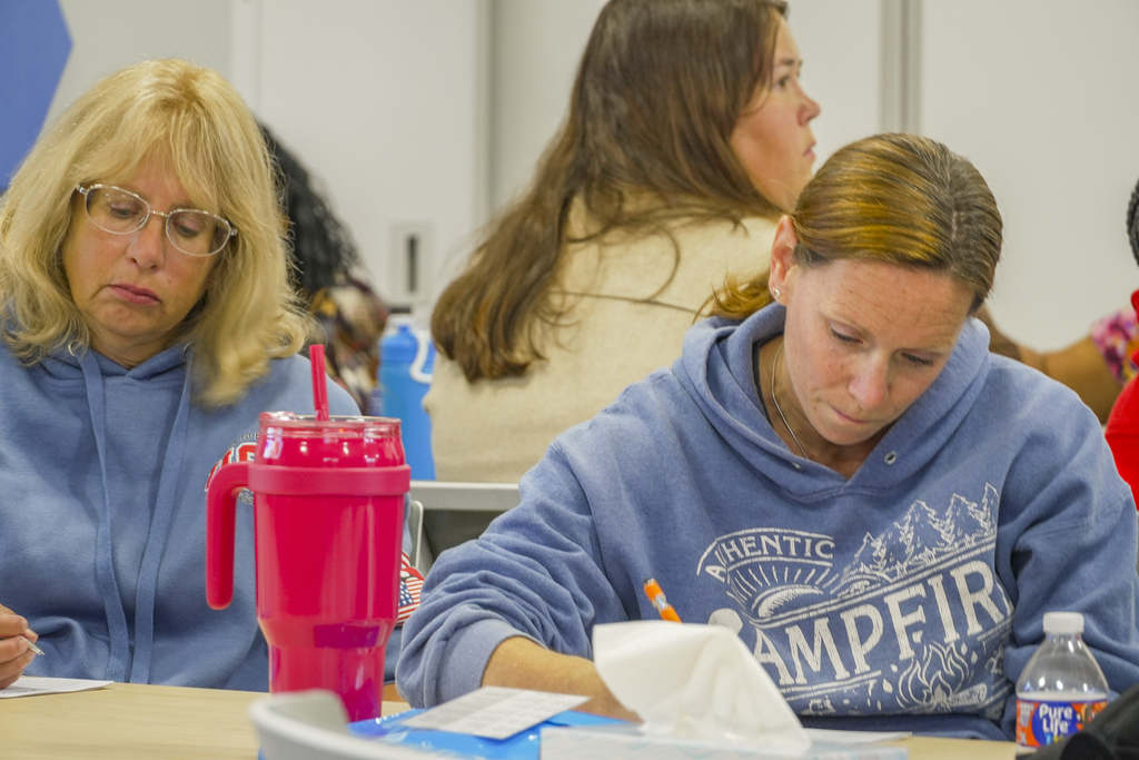 Two people sitting at a table taking notes