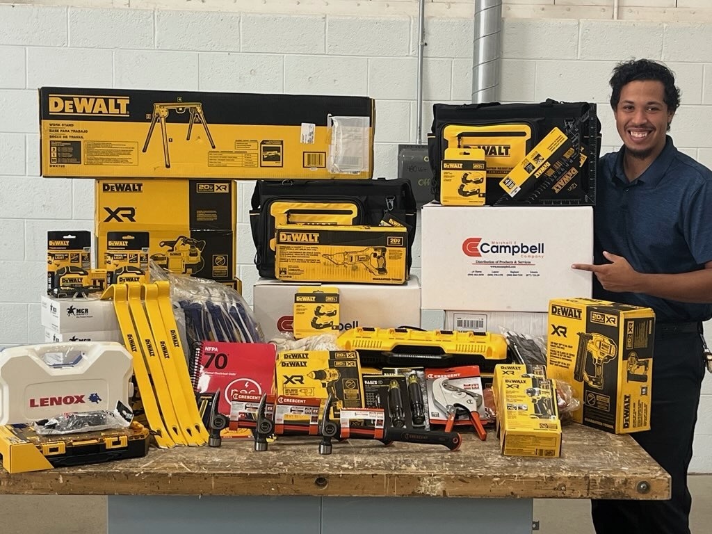 Construction Trades Paraprofessional Caleb Howell stands next to a display of donated items from Marshall E CAmpbell.