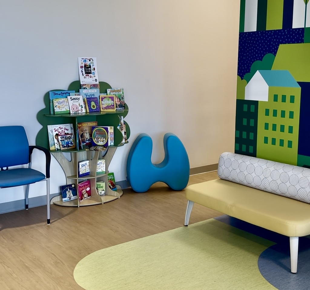 The new Talking Is Teaching space in the waiting room at the St. Clair County Health Department. The multi-shelf bookshelf is shaped like a tree and stocked with children's books.