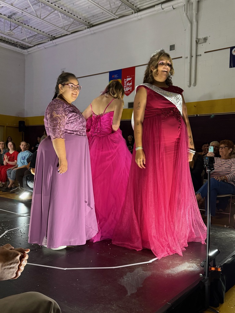 Three Woodland students wearing evening dresses pose on the runway during Fash Bash