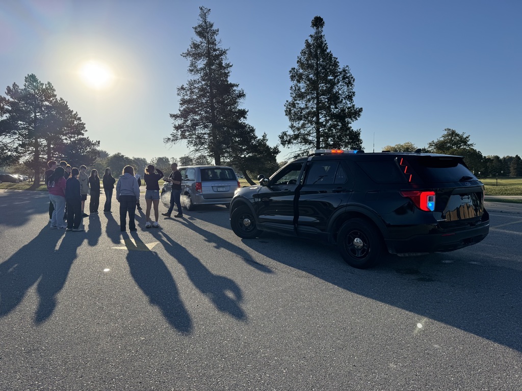 Students in TEC's Law & Public Safety program stand next to a mini van and decommissioned police cruiser to simulate a traffic stop.  