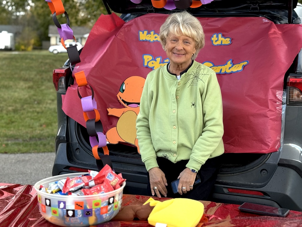 A woman sitting in front of a Pokemon-themed trunk featuring Charmander cutout and colorful paper chains.