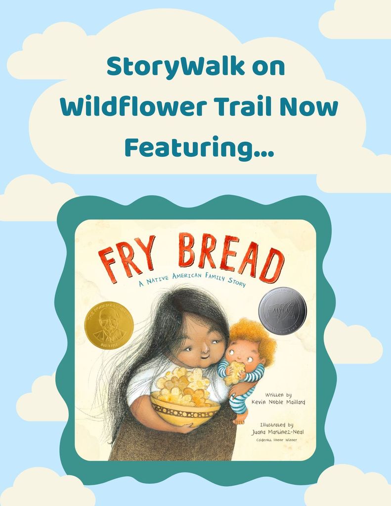 A colorful poster with clouds in the background reads “StoryWalk on Wildflower Trail Now Featuring…” Below the text is the book cover of Fry Bread: A Native American Family Story by Kevin Noble Maillard, illustrated by Juana Martinez-Neal. The cover shows a Native American woman holding a bowl of fry bread, smiling lovingly at a small child who is reaching for a piece.