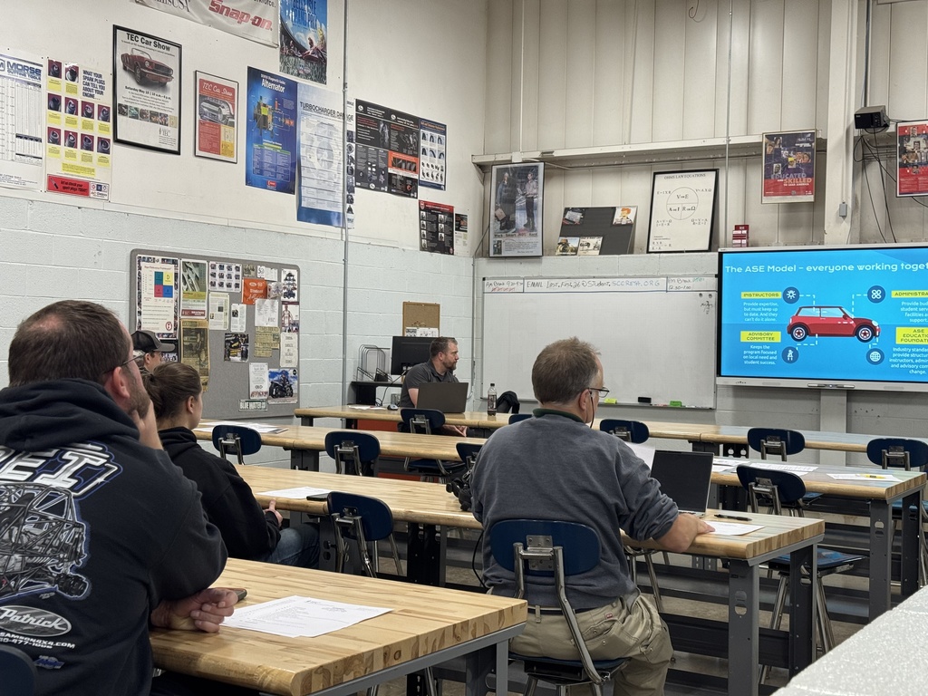 A TEC instructor displays a presentation on a screen to adults in a classroom