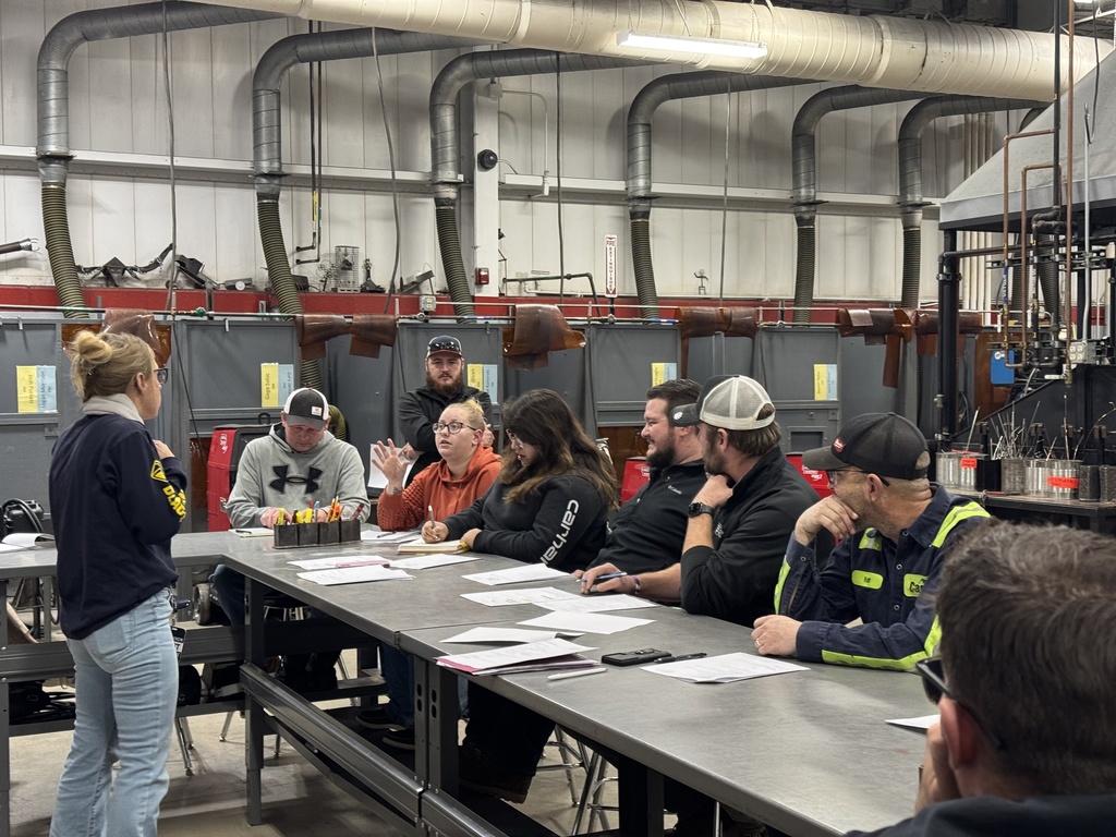 A TEC instructor talks to a room of adults seated at a table