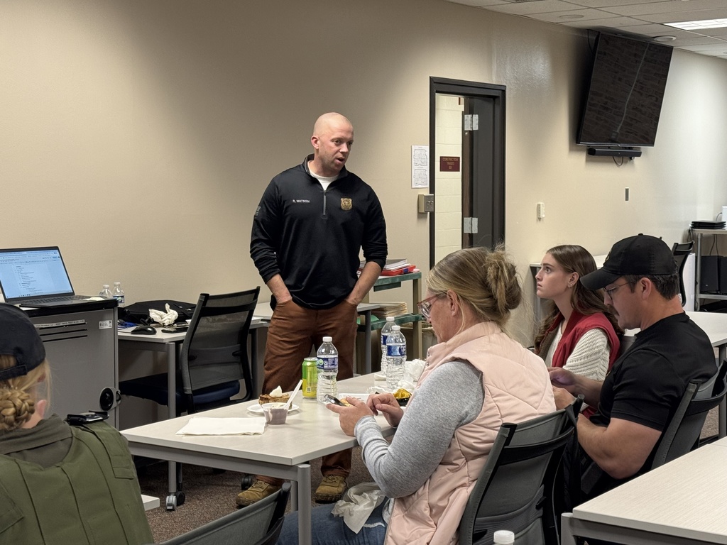 A TEC instructor talks to a room of adults seated at tables in a classroom