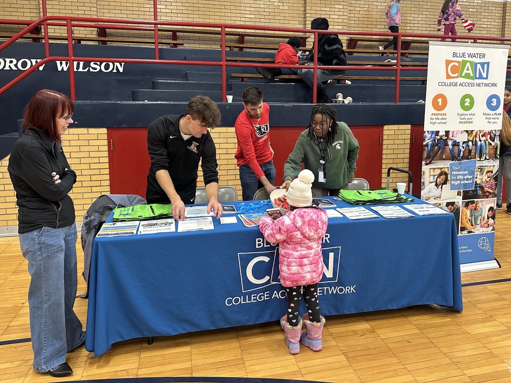 RESA staff stand at a table talking with a young child
