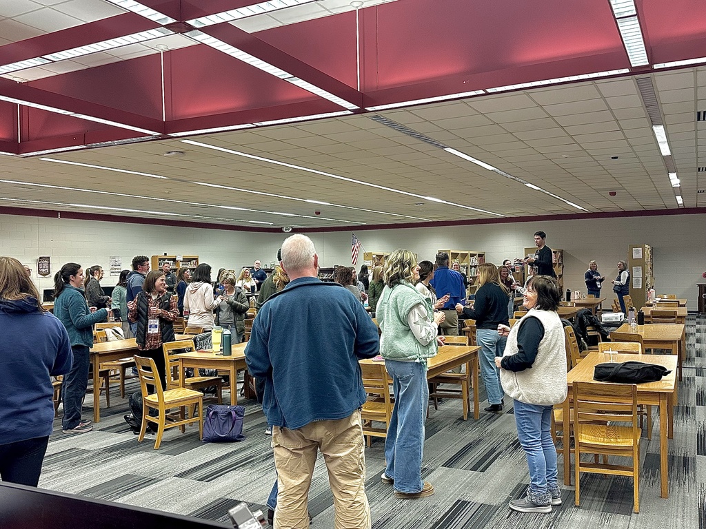 A room full of participants stand during a presentation