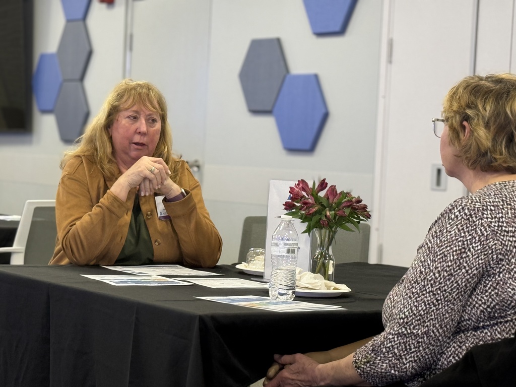 Two women seated at a table converse