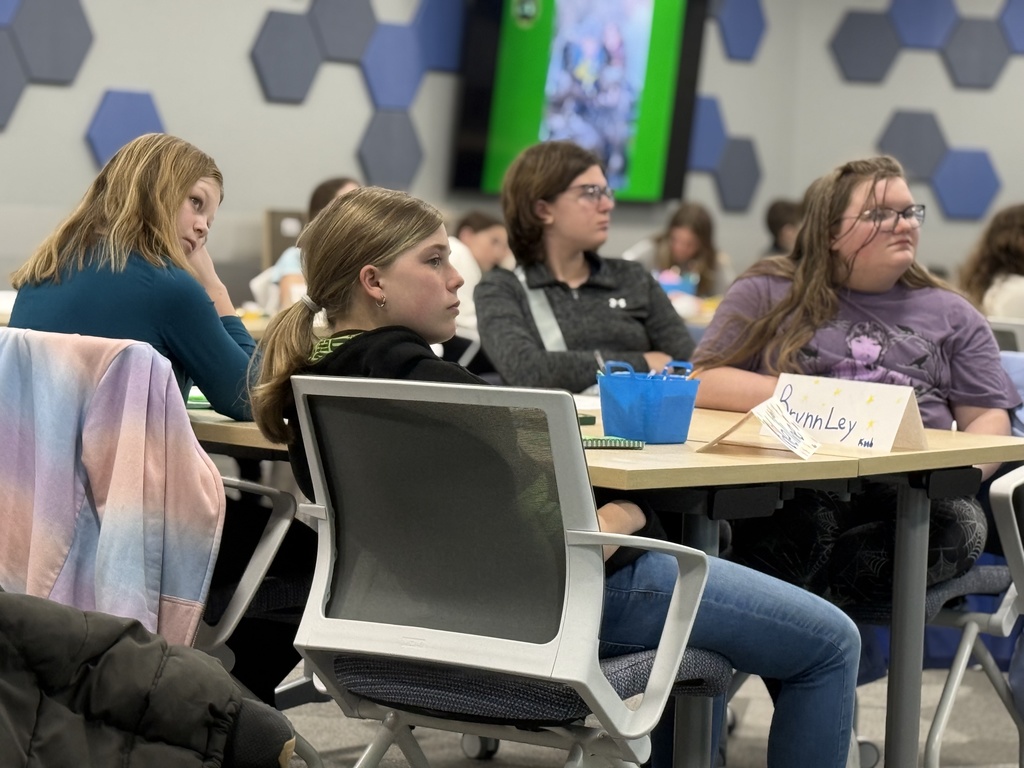 Students seated at tables in a classroom setting listen to a presentation by the DNR