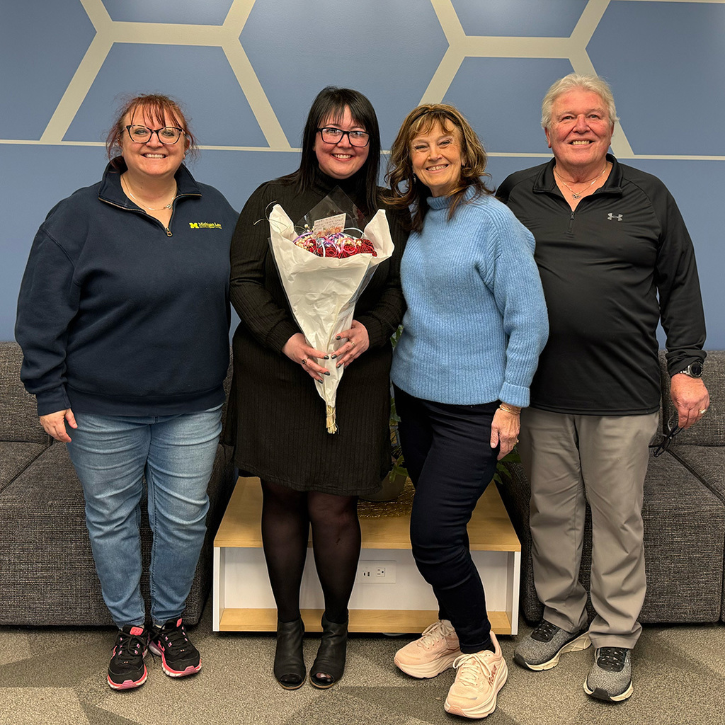 Angela Jackson holding a bouquet of flowers stands with her sister and parents.