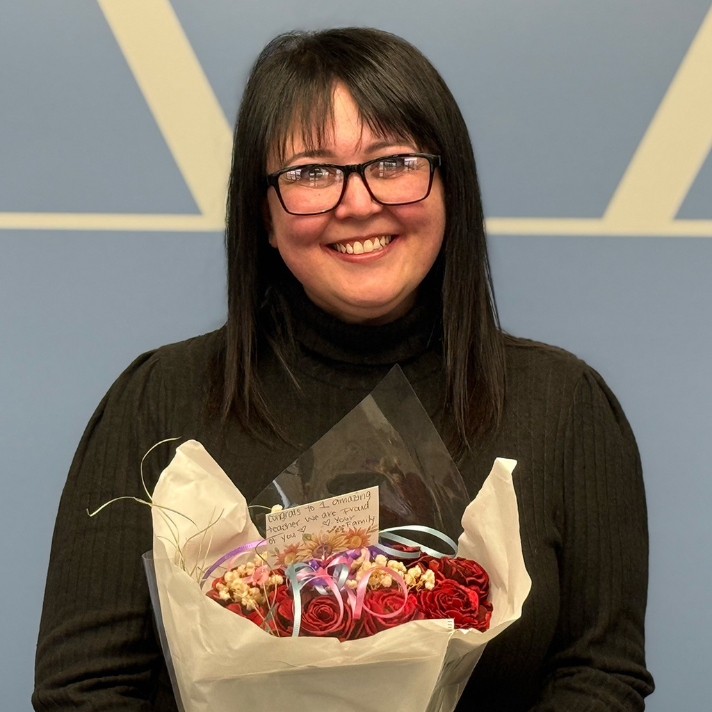 A smiling Angela Jackson holds a bouquet of roses from her family.