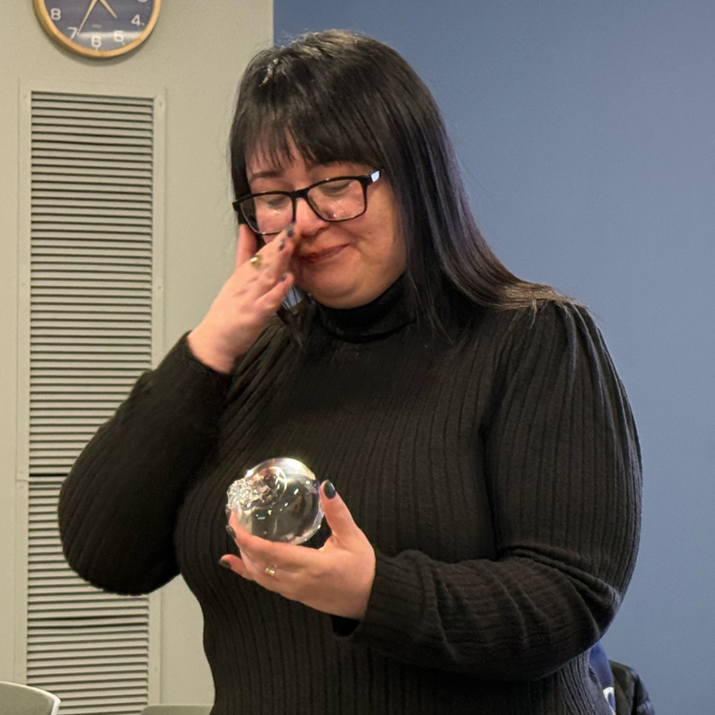Angela Jackson wipes a tear from her face while holding the glass apple she was presented by the RESA Board of Education