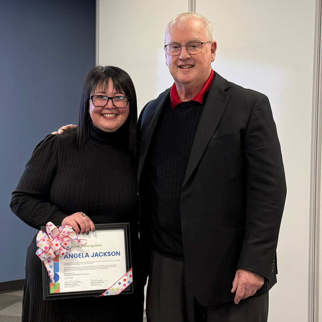 Angela Jackson holds her certificate of recognition stands with board president Mike McCartan