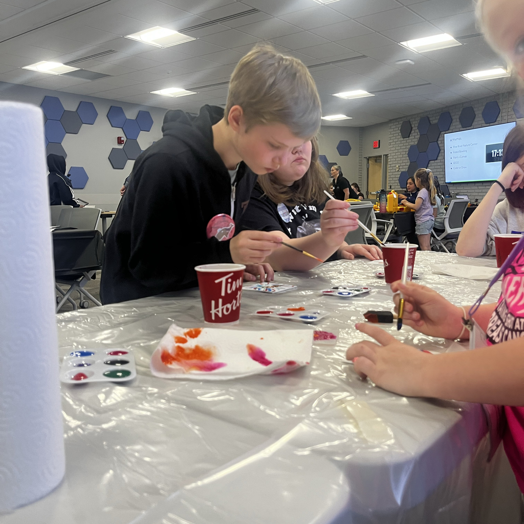 Students sit at a table painting with watercolors