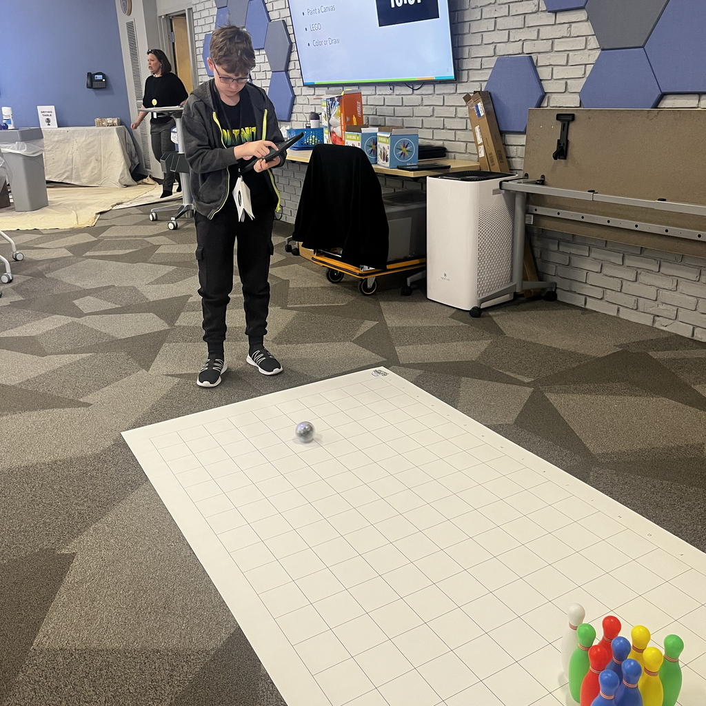 A student uses an iPad to program a mini bowling game