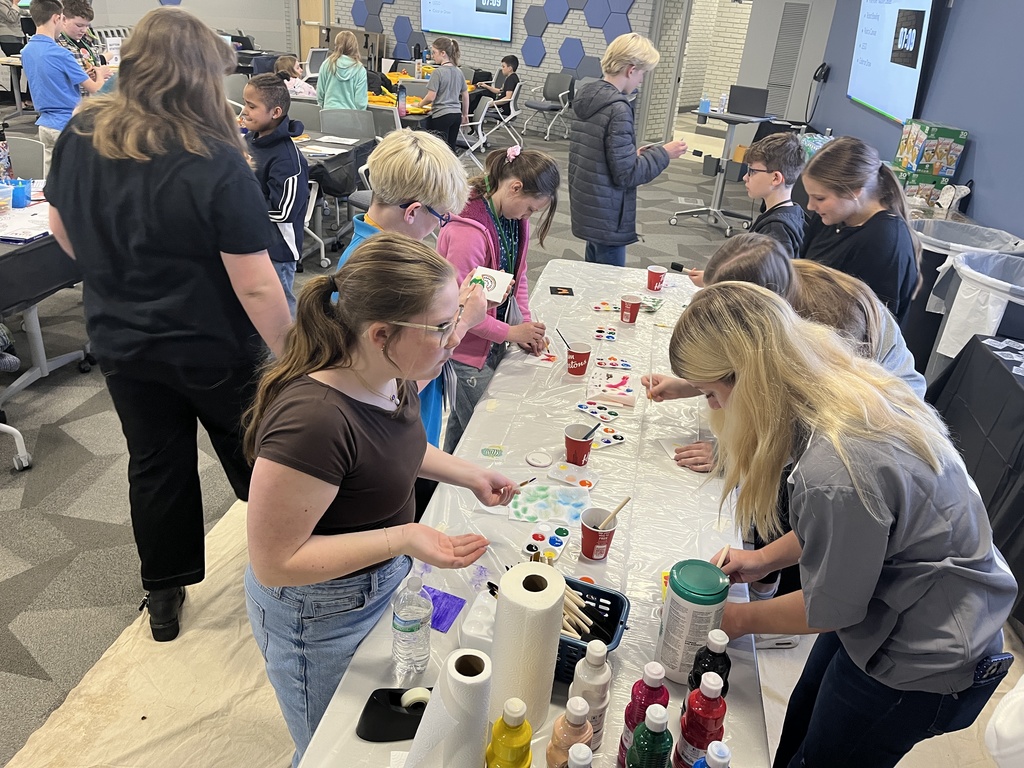 Students standing at a table paint with watercolors