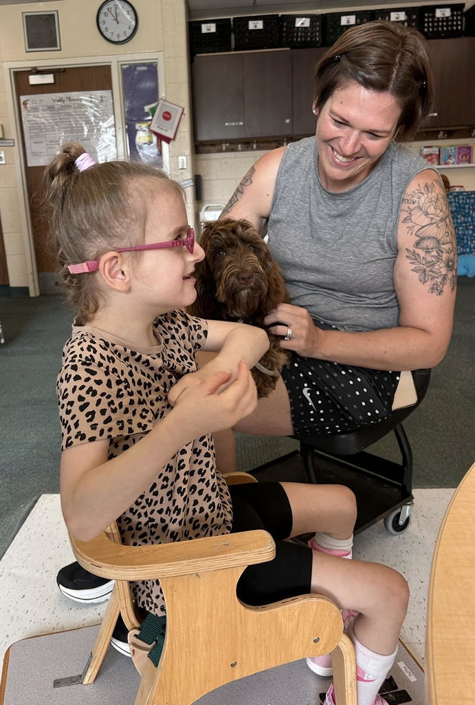 Handler Chelsey Hull holds Frannie while a student pets her