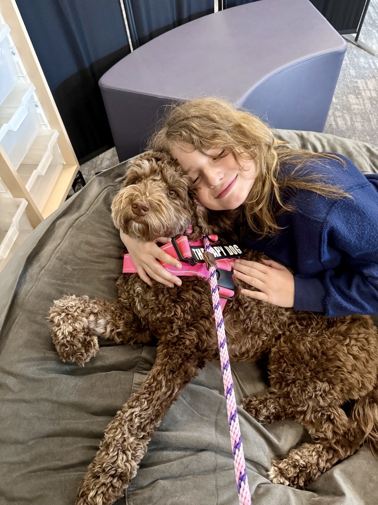 A student hugs Frannie the Therapy Dog