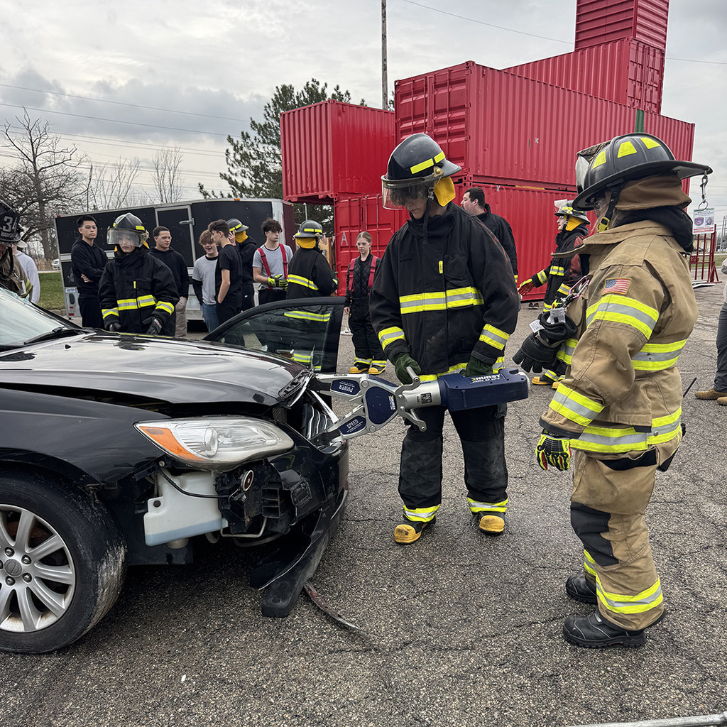 A TEC student uses the extracation tool on the front end of a car during a training exercise