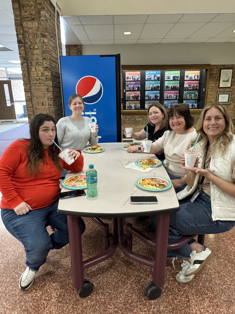 Five TEC staff members sit together at a cafeteria table enjoying smoothies and lunch during Teacher Appreciation Week