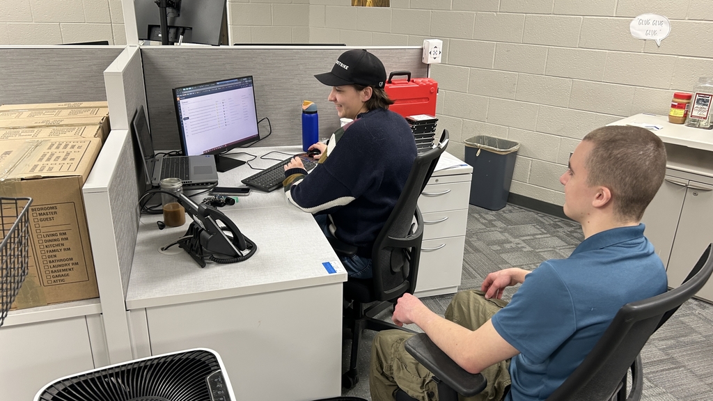 A TEC student observes a SCCRESA IT staff member working at a workstation during a job shadow experience