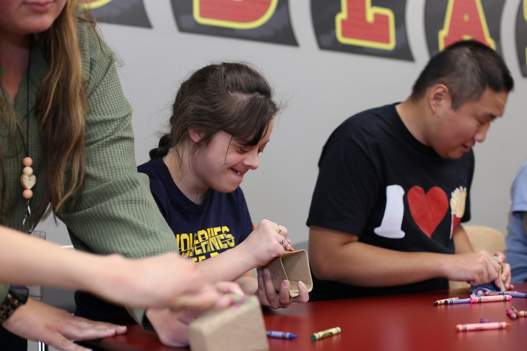 A student smiles while decorating a personalized flower planter during Woodland Developmental Center’s Garden Club.