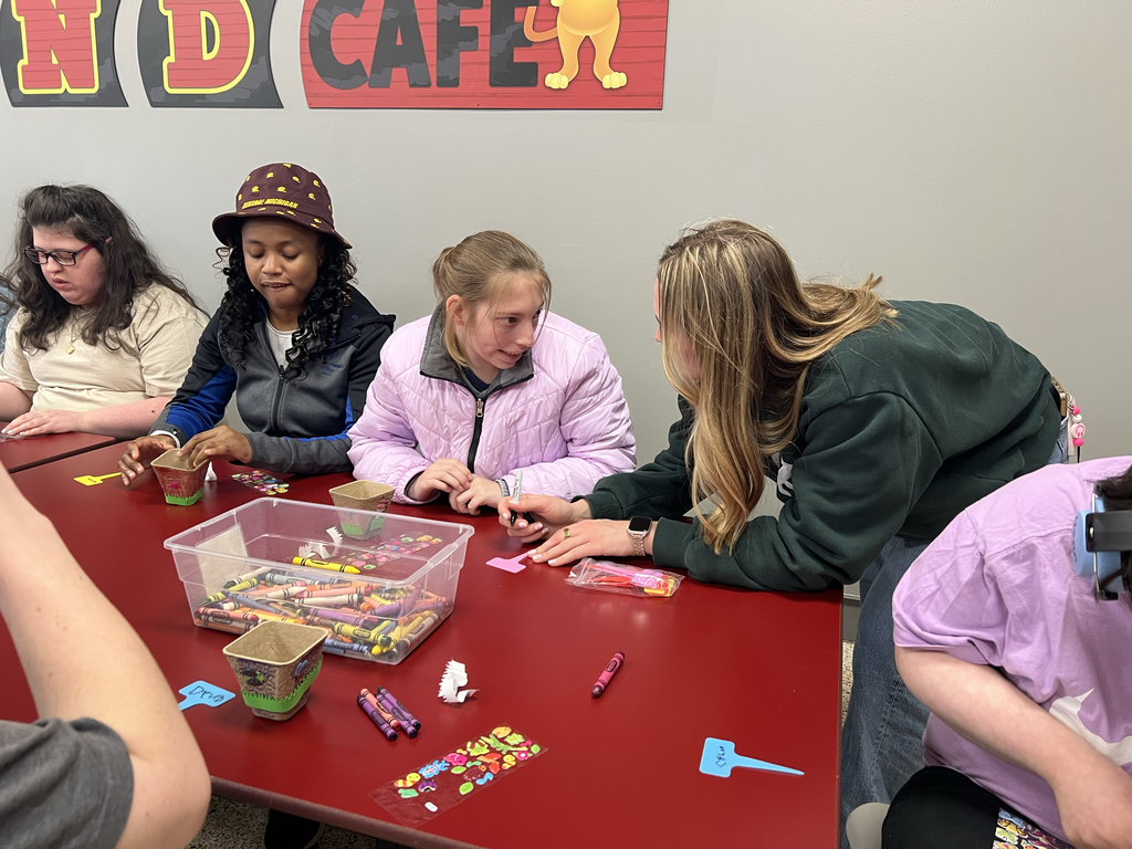 A staff member talks with students as they decorate flower planters during Woodland Developmental Center’s Garden Club activity.