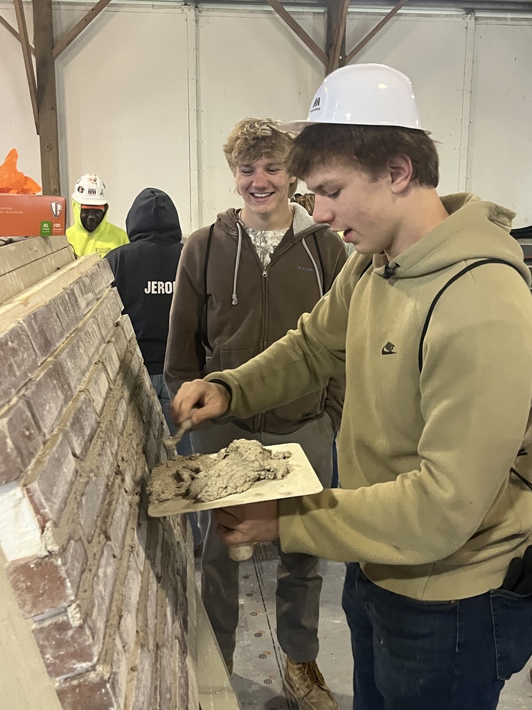 A St. Clair TEC student practices masonry skills by spreading mortar onto a brick wall during a hands-on activity at the Blue Water Building Trades Career Fair