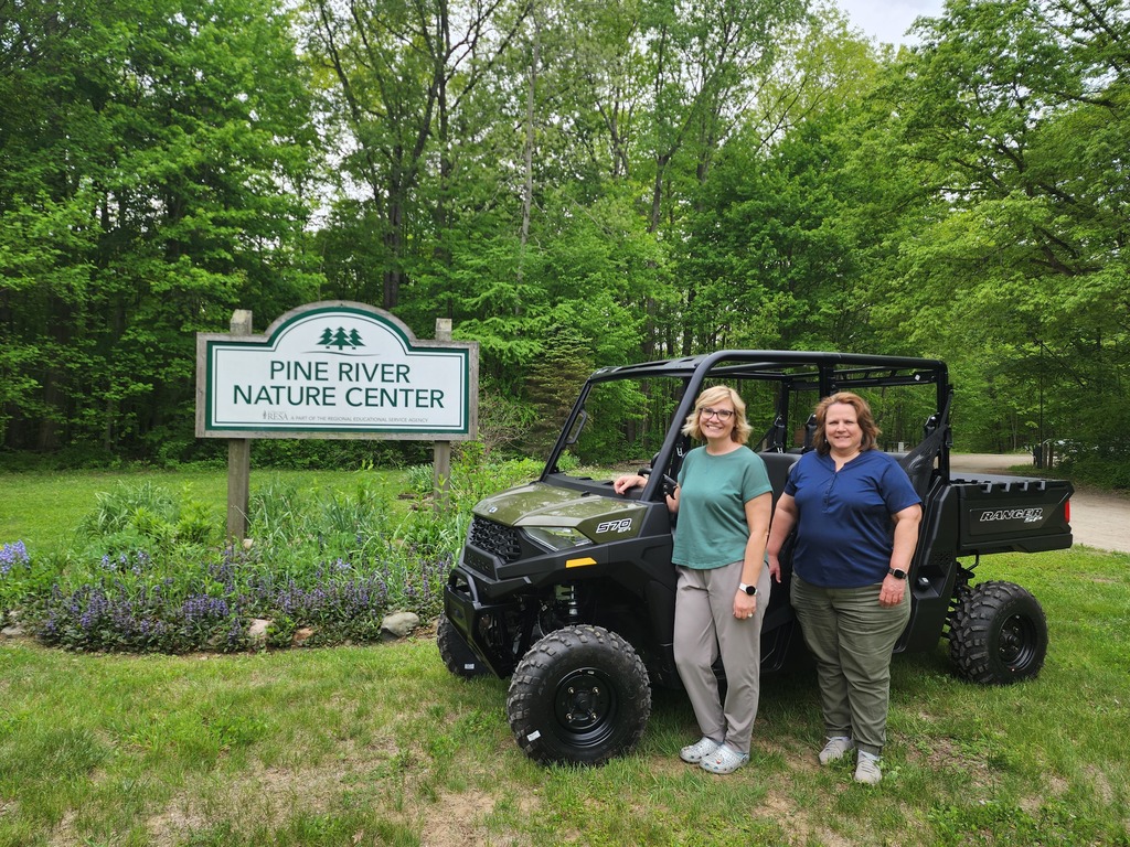 Sarah Nelson and Monique Werner pose with the new Polaris Ranger Crew 4x4 at the entrance of the Pine River Nature Center.  