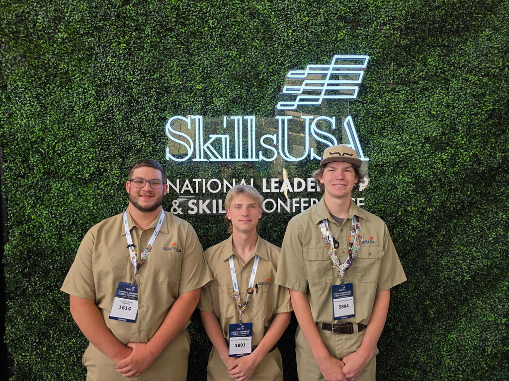 TEC students and SC4 students stand in front of an illuminated SkillsUSA background.