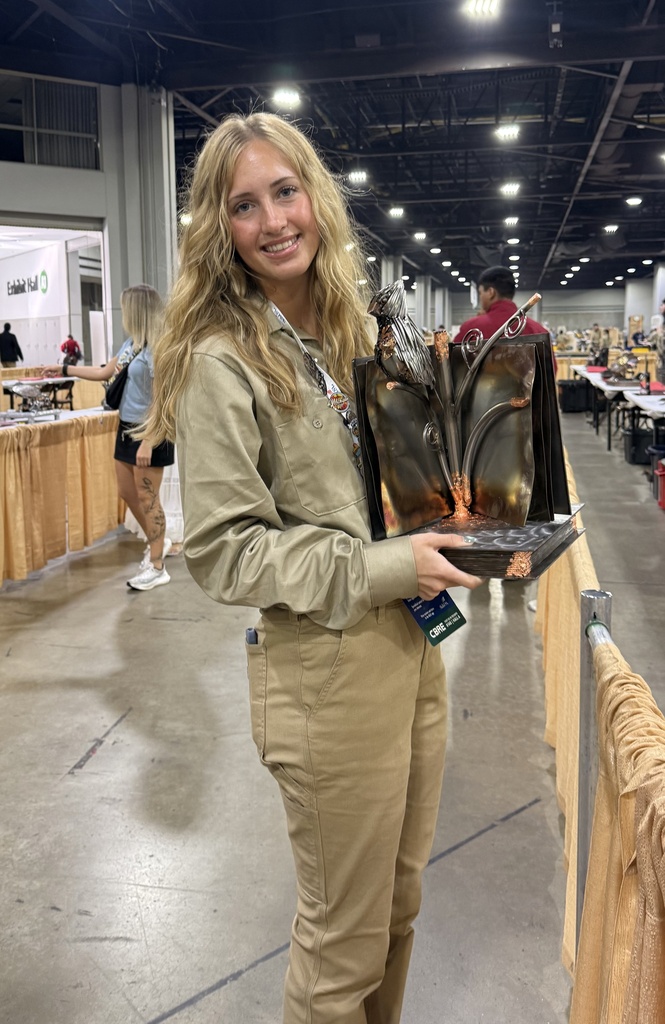 Rori Cowhy poses while holding her welding sculpture