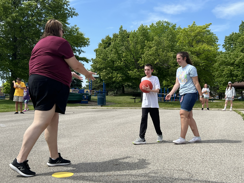 Two staff members walk next to a student holding a basketball