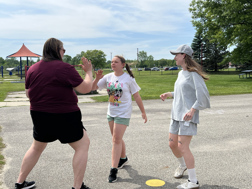 A Woodland staff member high-fives a student as another staff member looks on