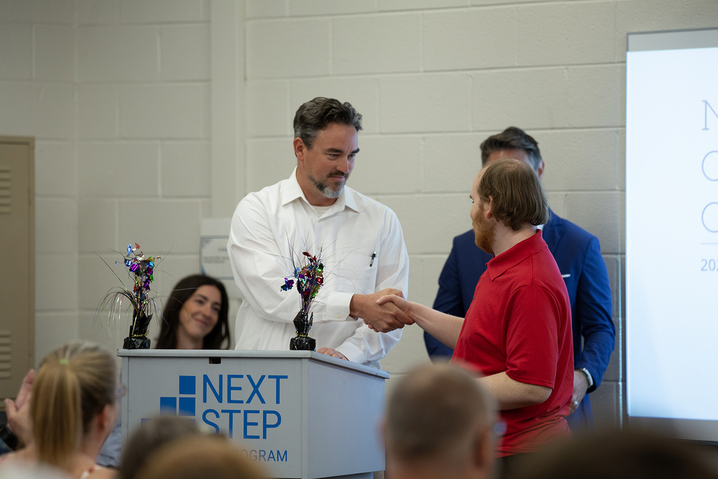 A Next Step staff member shakes hands with a student during the completion ceremony